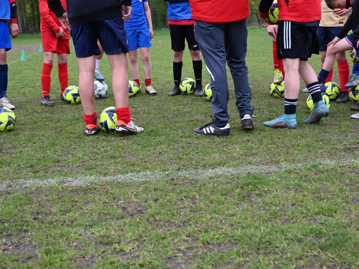 Voetballers in cirkel met een aantal voetballen.