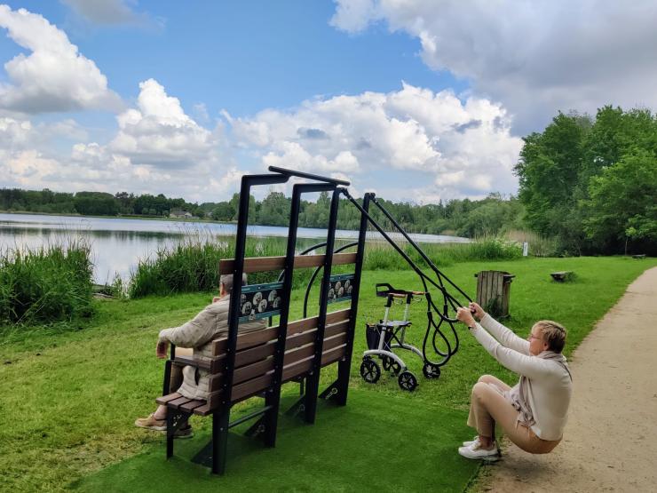 Twee mensen gebruiken de beweegbank aan 'de Plas' van Rotselaar.