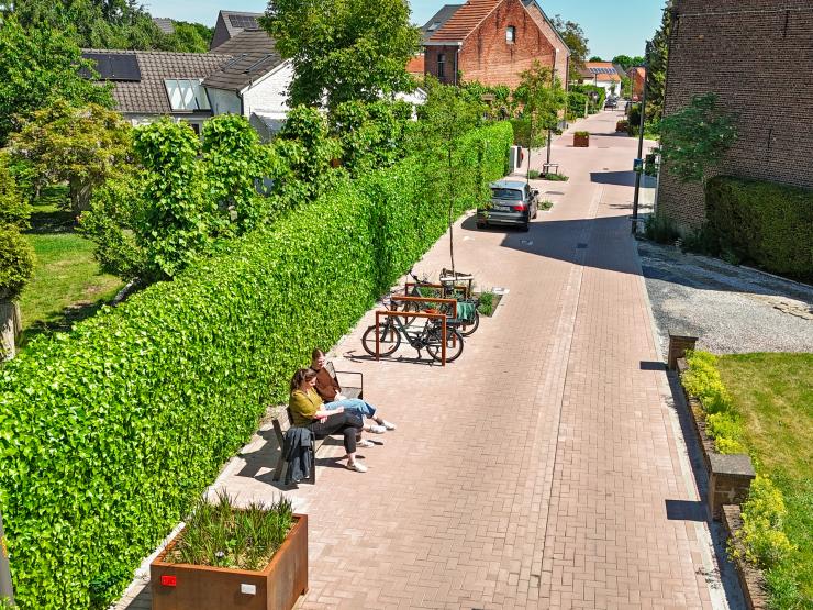 Woonerf in de Groenstraat met een auto, fiets in fietsbeugels en twee mensen op een bankje.