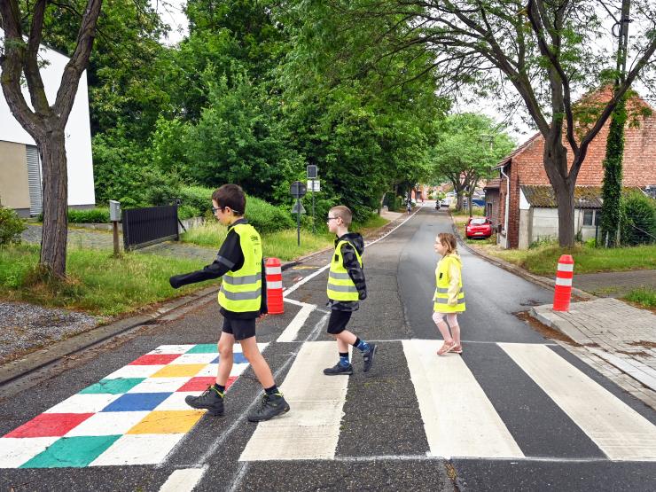 Kinderen op het zebrapad aan de wegversmalling in de Sint-Pietersstraat, met links tekeningen in de voetgangersstrook.