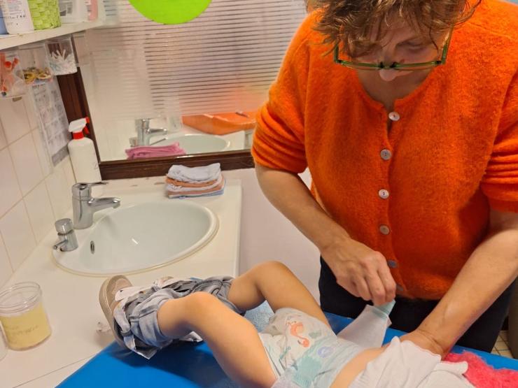 Begeleider kinderopvang ververst een baby.